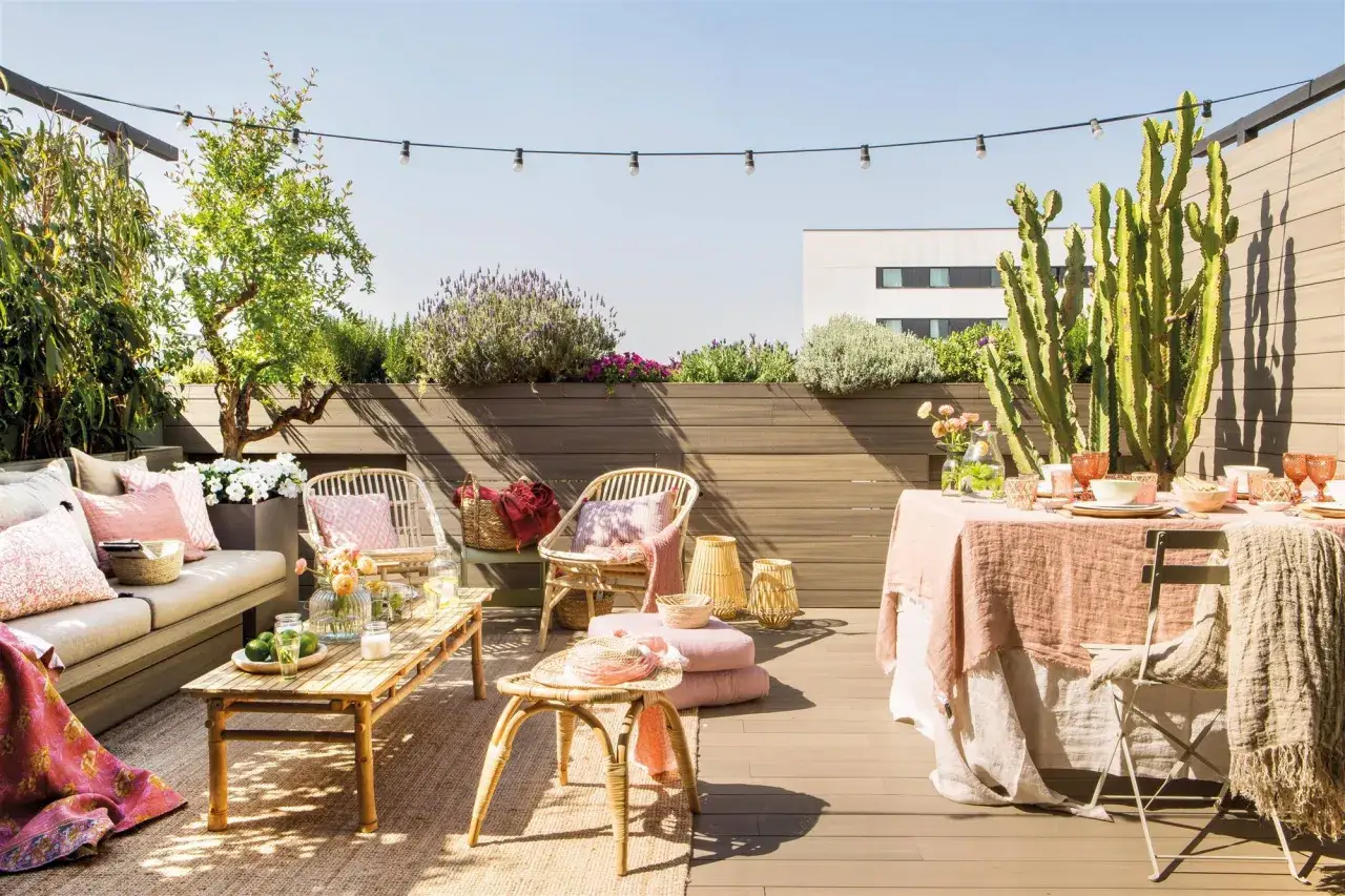 Terraza de ático lista para disfrutar. Una reforma que invita a la relajación con mobiliario de ratán, textiles suaves y plantas exuberantes.