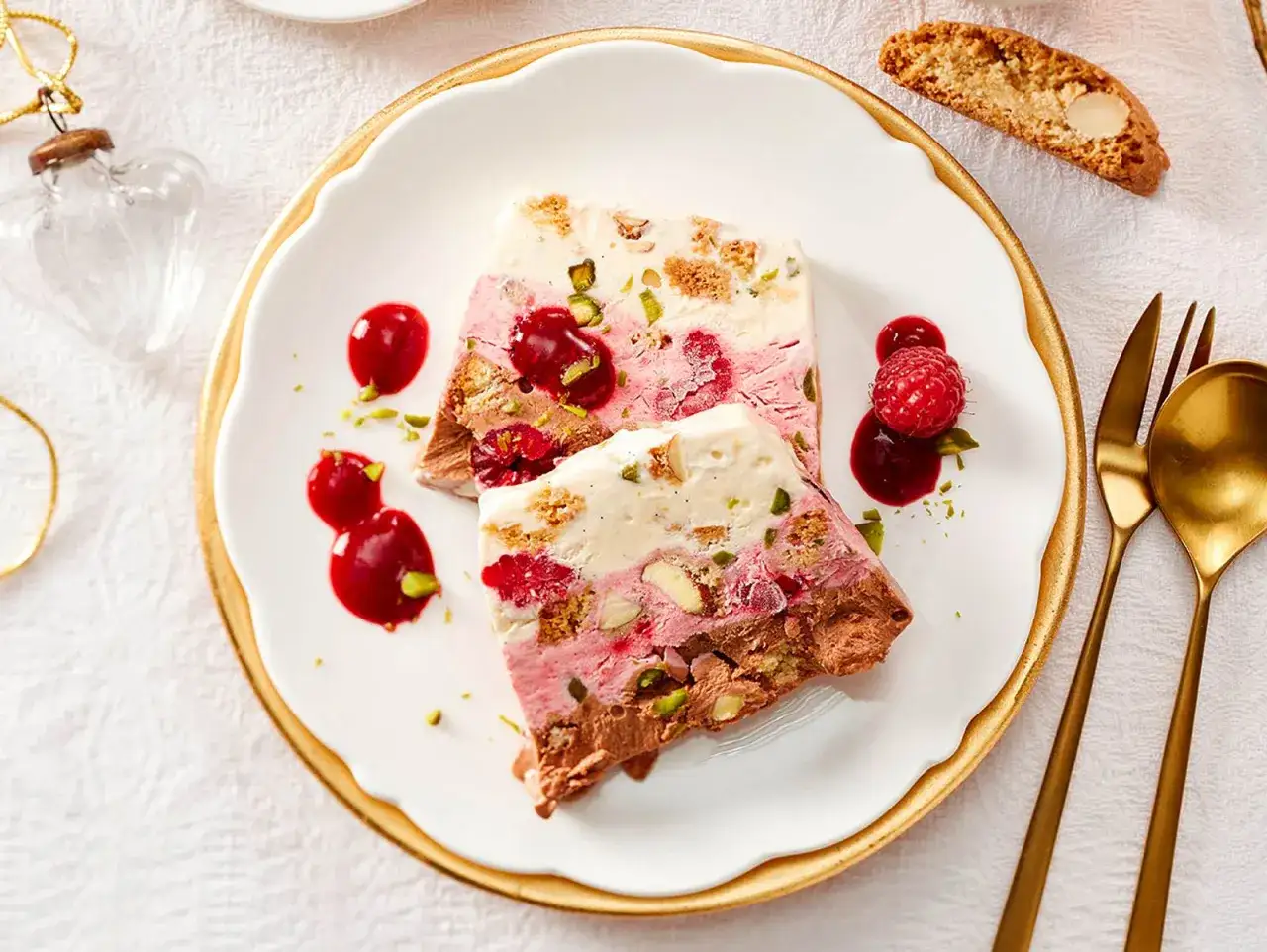 Gefrorenes Dessert mit Schichten aus Schokolade, Beeren und Nüssen, garniert mit Beeren und Sauce.