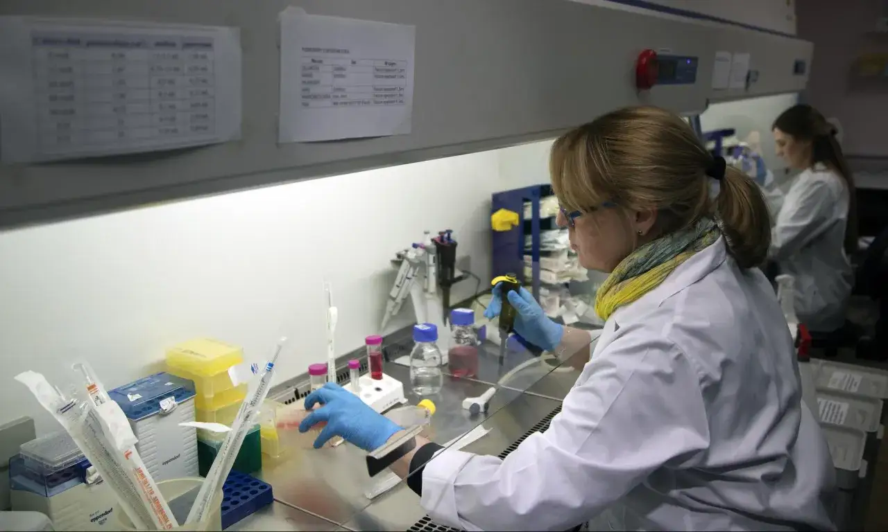 Naukowczyni w laboratorium pracuje z pipetą i próbówkami.