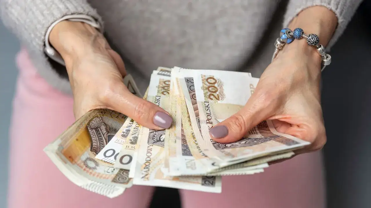 Dłonie trzymające plik banknotów 200 zł. To może być wypłata, oszczędności, a może nawet słynne "kosiniakowe".