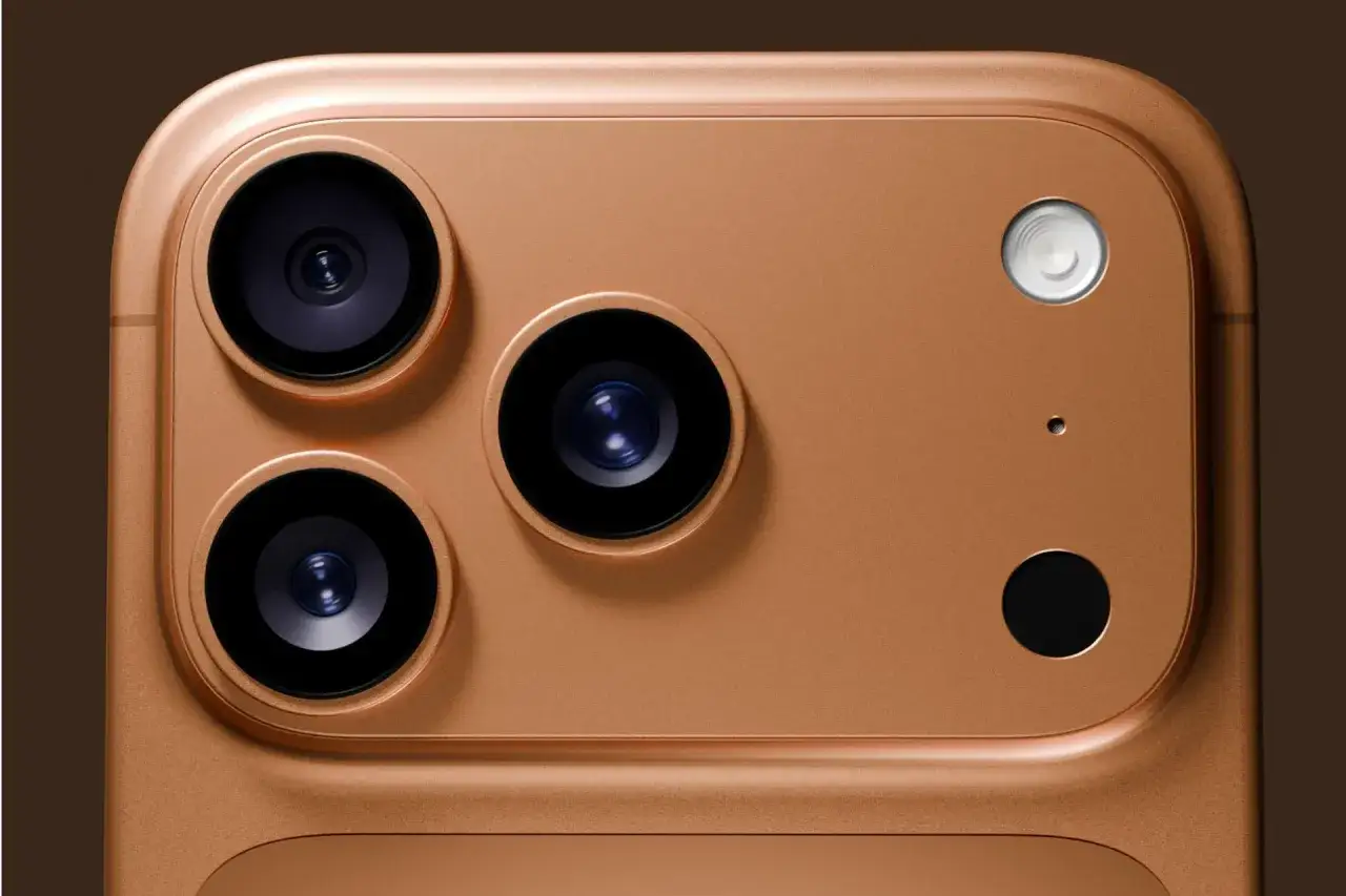 Gros plan sur le module caméra d'un iPhone couleur or. Trois objectifs noirs et un flash blanc sur un fond brun.