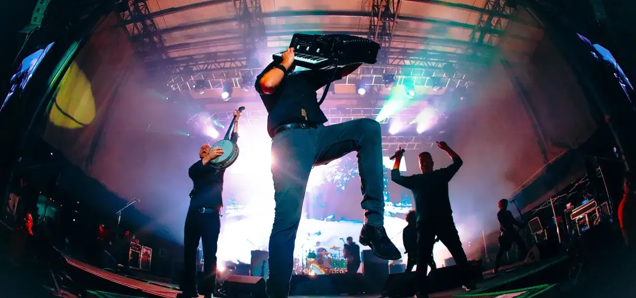 Energetyczne koncerty Dropkick Murphys: muzyk gra na akordeonie, inny na banjo, a w tle wokalista z mikrofonem.