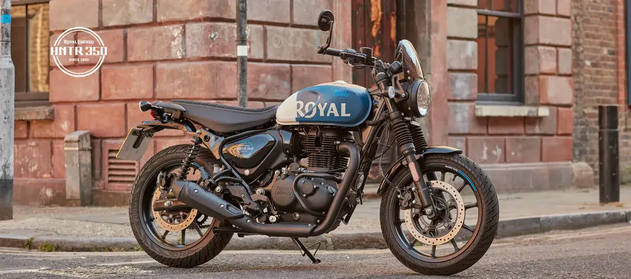 Stylowy motocykl Royal Enfield Hunter 350 z niebiesko-białym malowaniem zbiornika, zaparkowany na ulicy.