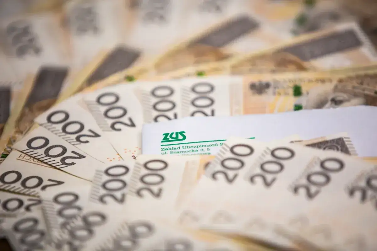 Stos banknotów 200 zł z logo ZUS. Mały zus i dużo pieniędzy.