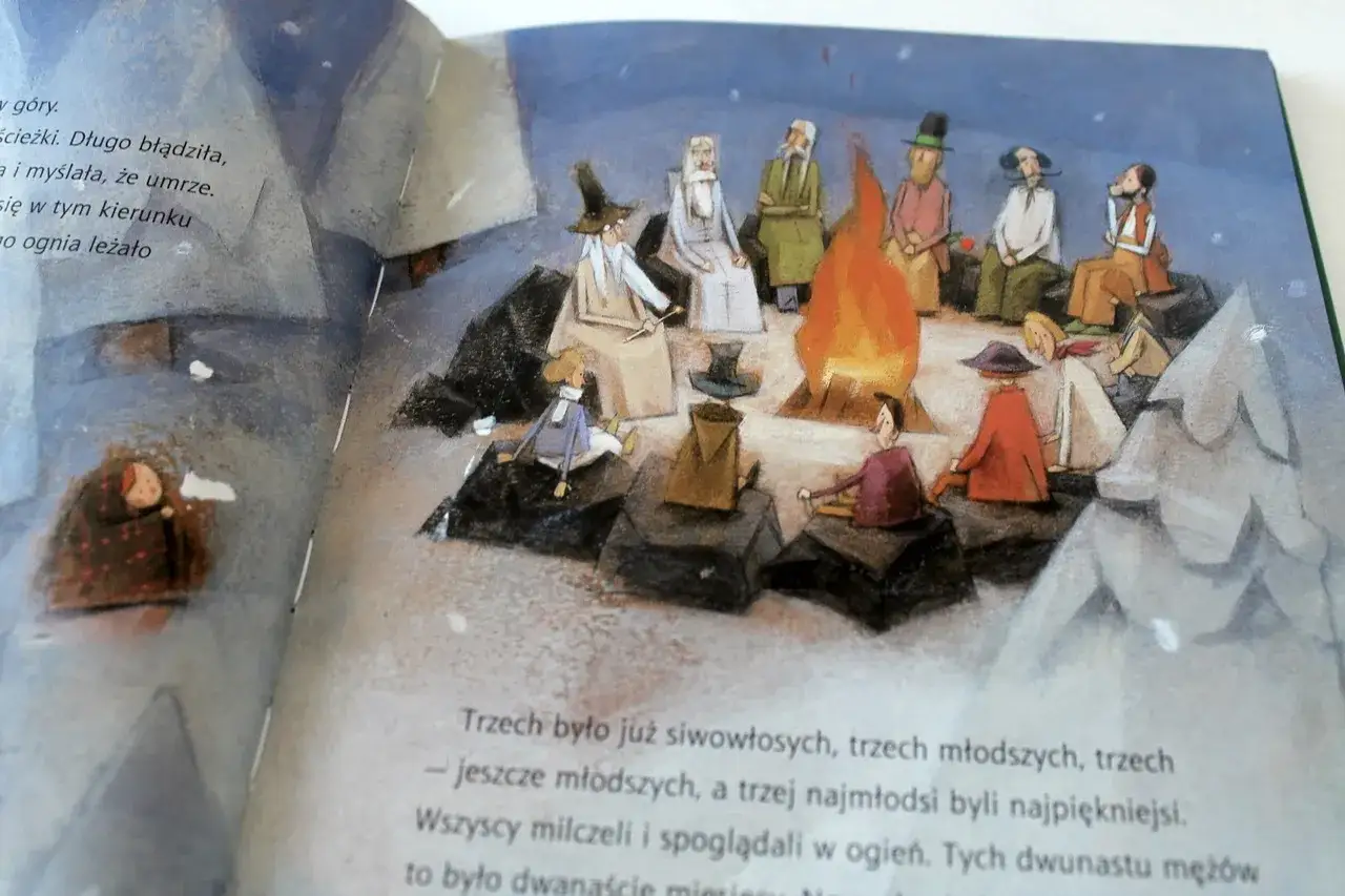 Ilustracja przedstawia grupę ludzi siedzących wokół ogniska, z dzieckiem przykrytym kocem po lewej stronie.