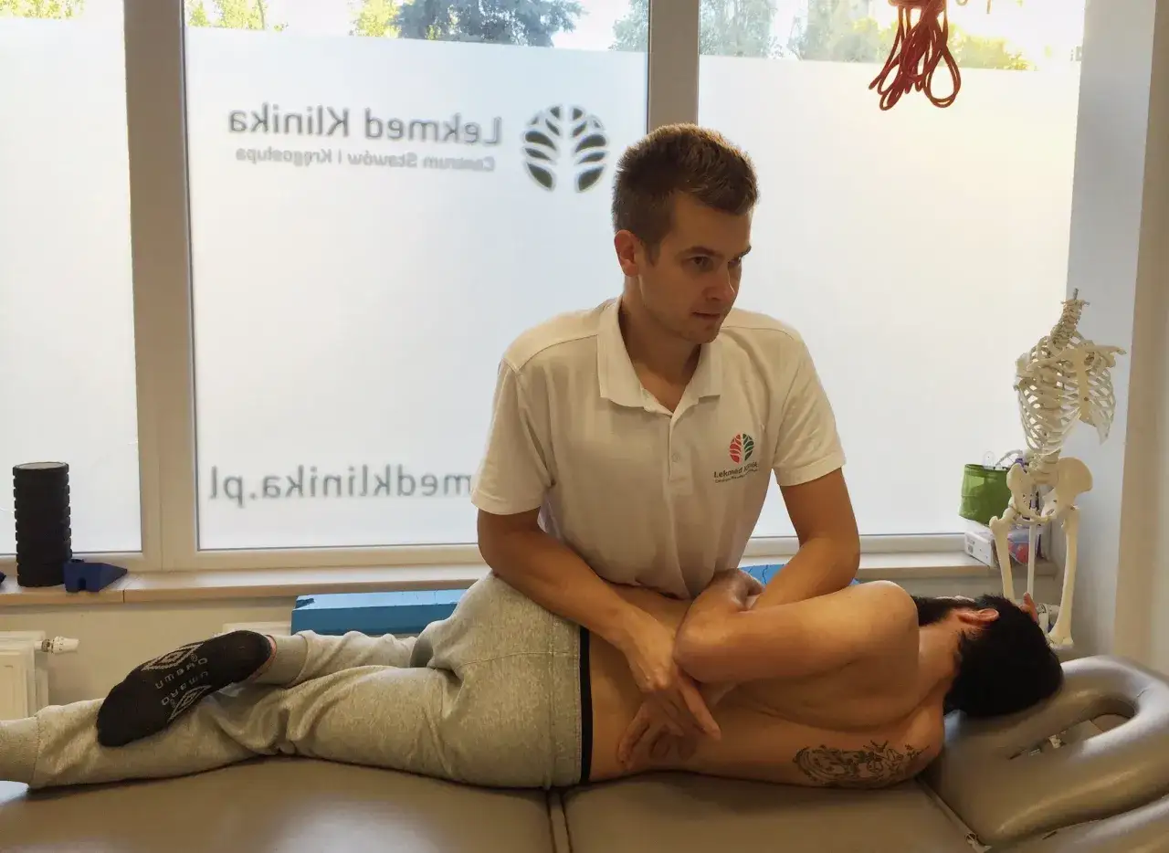 Fizjoterapeuta wykonuje terapię manualną, pomagając pacjentowi po nastawieniu kręgosłupa.