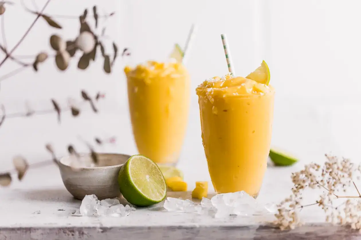 Zwei cremige Mango-Lassis mit Limette und Kokosraspeln. Perfekt nach dem getrocknete Mango einweichen.