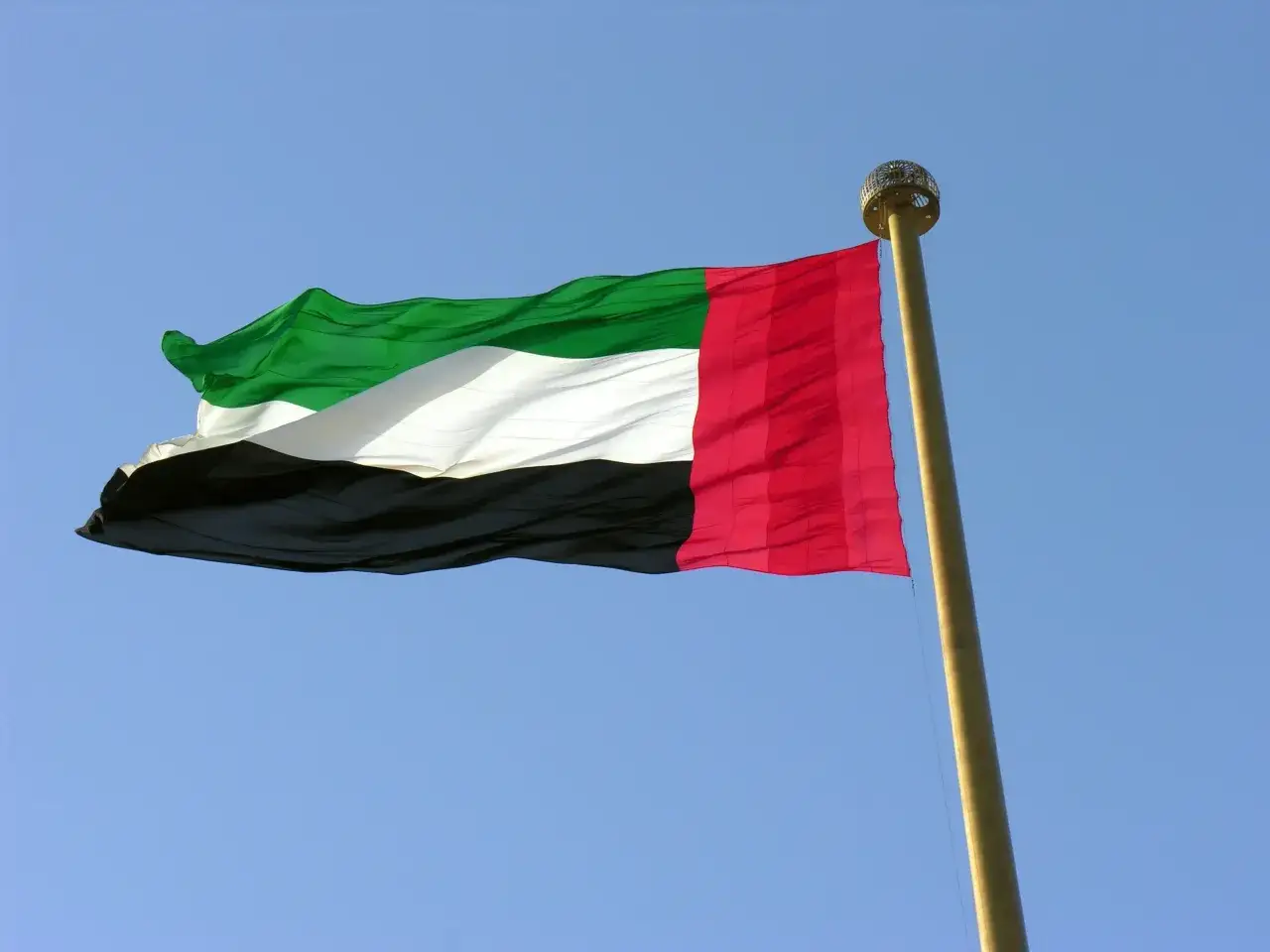 Flaga Zjednoczonych Emiratów Arabskich powiewa na tle błękitnego nieba. To kraj, który fascynuje.