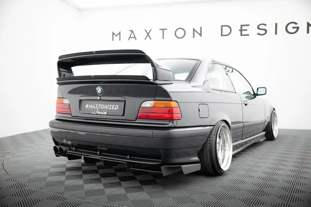 Czarne BMW E36 z tuningowym zderzakiem, dyfuzorem i dużym spoilerem.