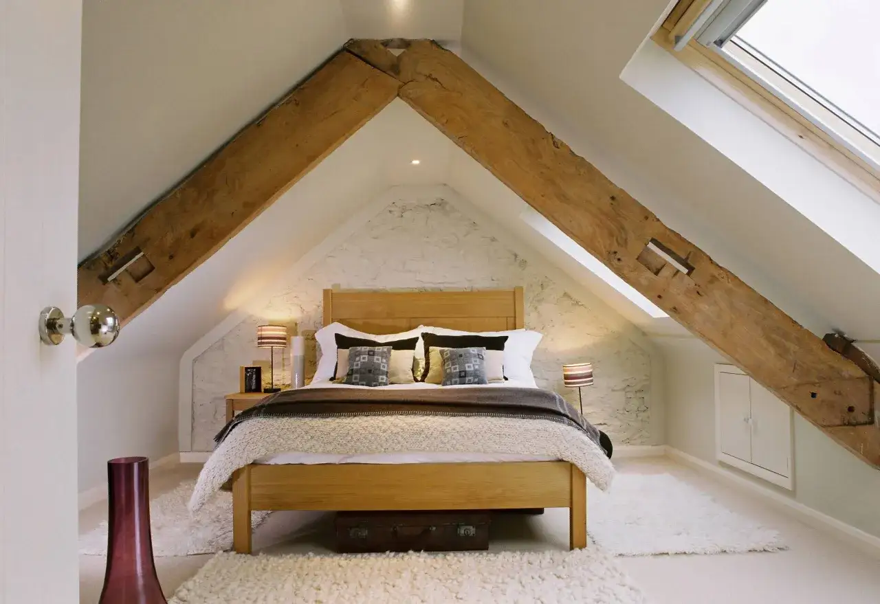 Dormitorio acogedor bajo un tejado con vigas de madera expuestas, ideal para levantar tejado para hacer buhardilla.