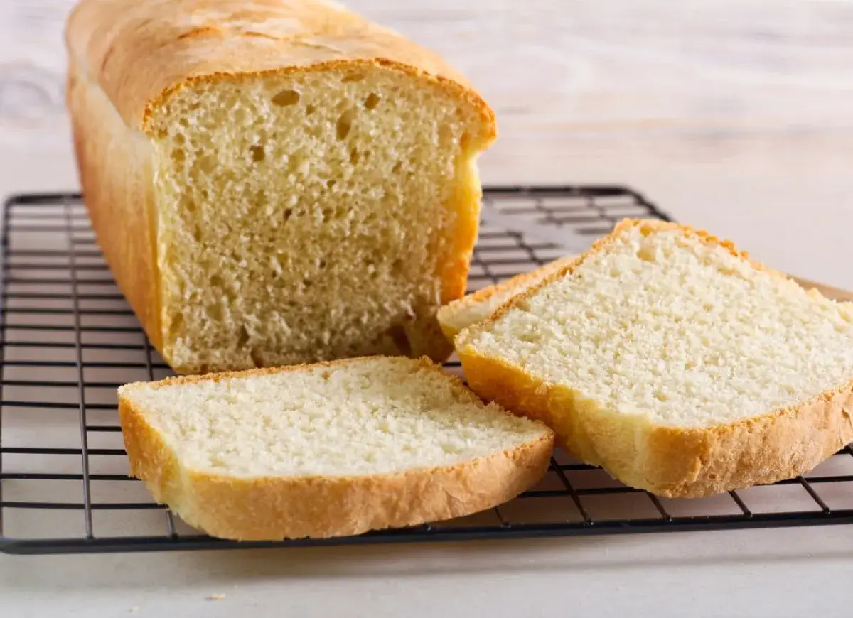 Świeżo upieczony chleb tostowy na kratce, z kilkoma kromkami obok. Idealny na śniadanie, ale warto sprawdzić chleb tostowy kcal.