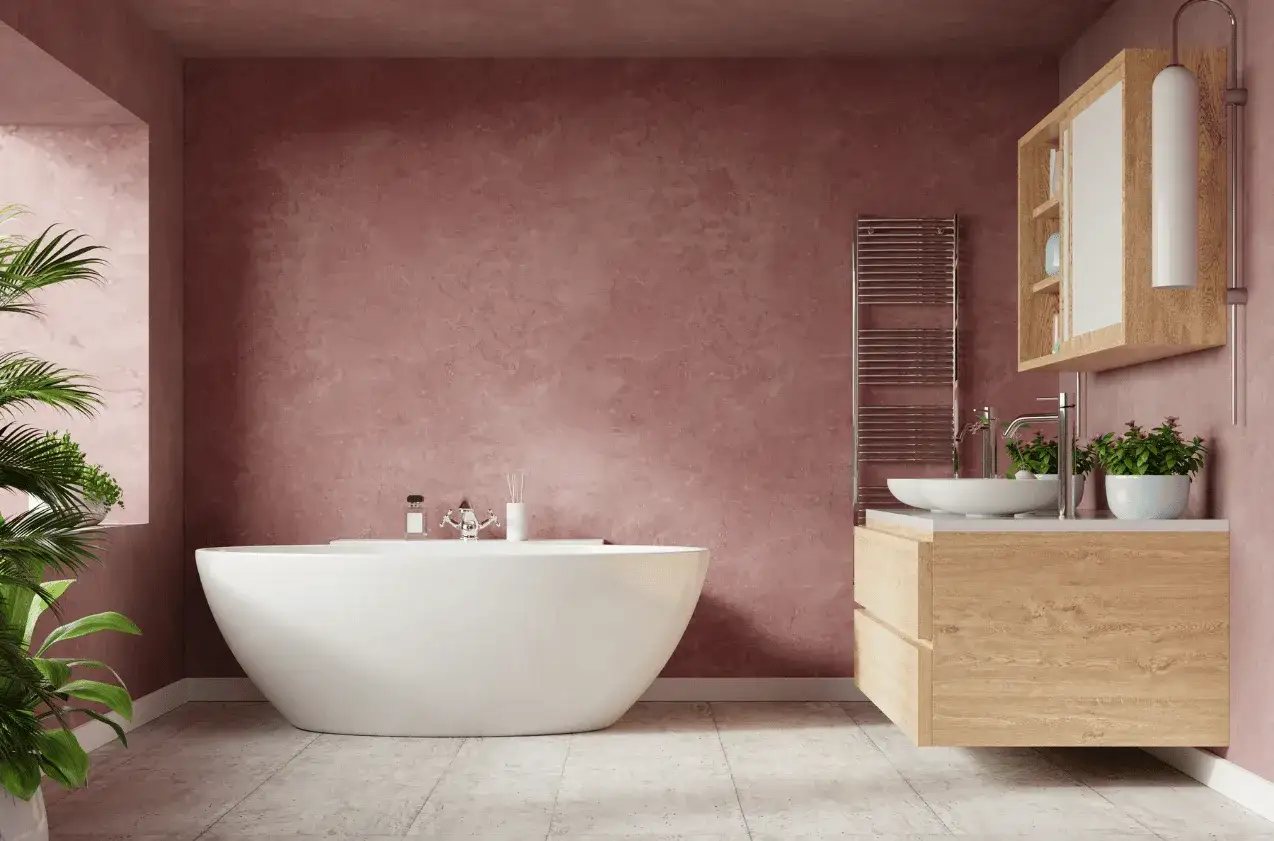 Un baño moderno con bañera independiente y tocador de madera. Las paredes de color rosa empolvado y las plantas aportan un toque acogedor a estos baños rústicos.