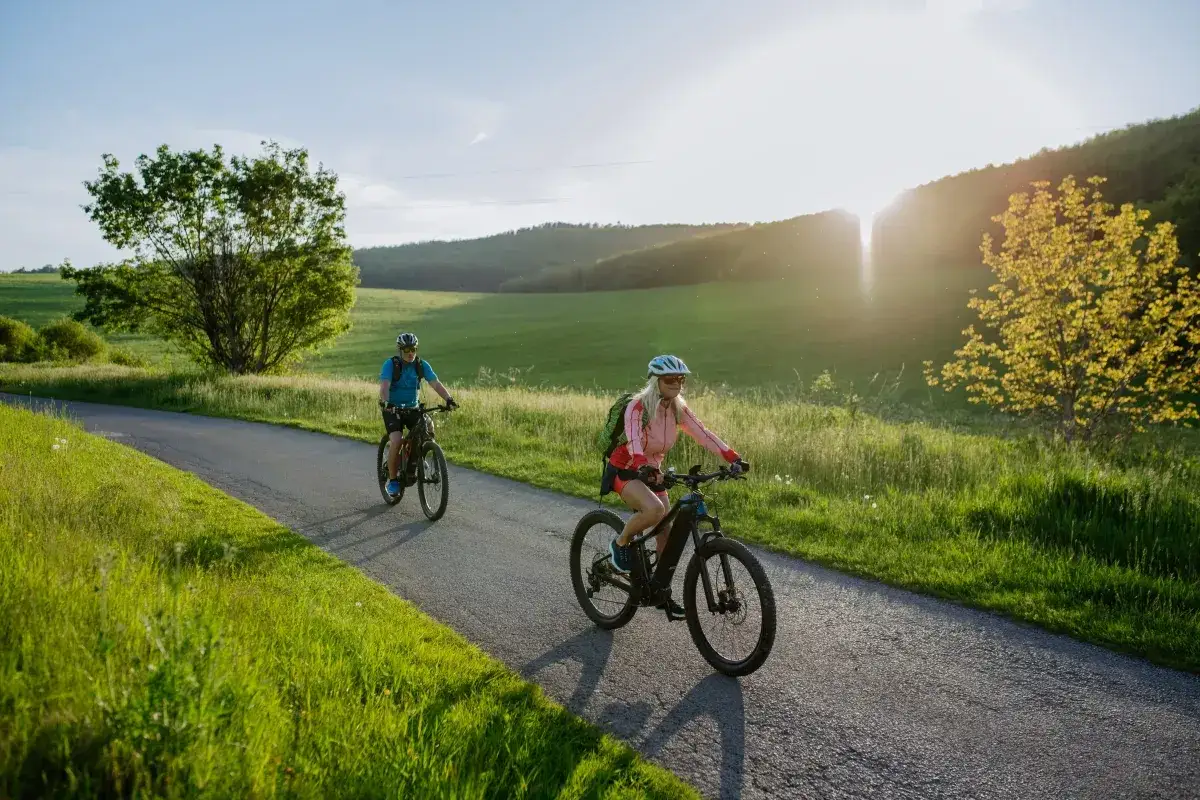 Dwie osoby na rowerach elektrycznych cieszą się malowniczą trasą. Dofinansowanie do roweru elektrycznego ułatwia takie wycieczki.