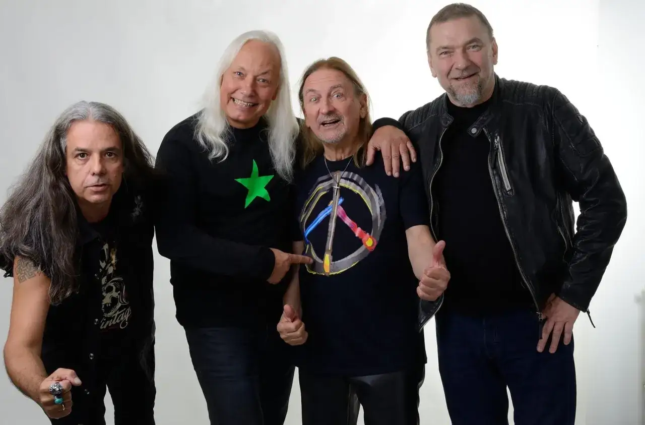 Czterech mężczyzn, TSA Dream Team, pozuje do zdjęcia. Dwóch z nich ma długie włosy, jeden w czarnej koszulce z zieloną gwiazdą, drugi w koszulce z symbolem pokoju.
