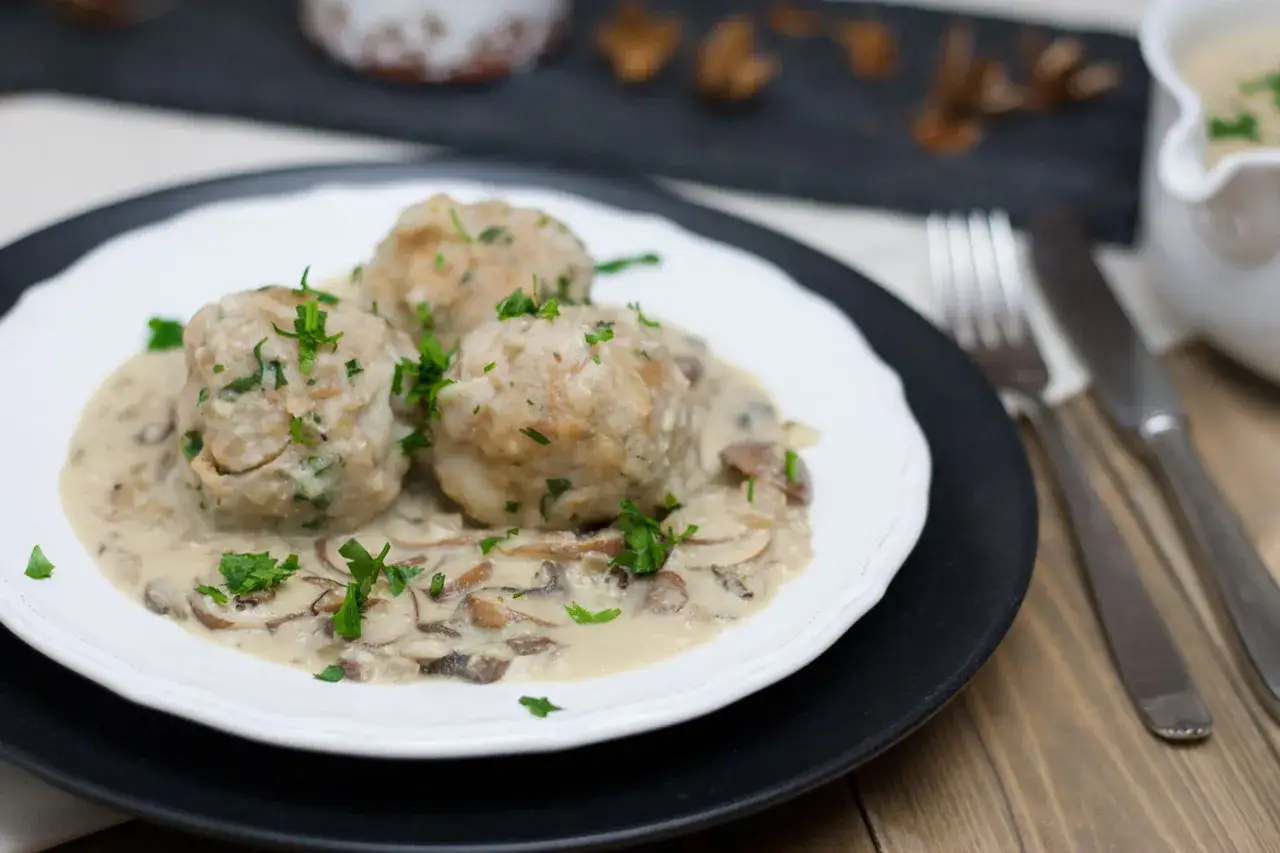 Vegane Semmelknödel in cremiger Pilzrahmsoße, garniert mit frischer Petersilie. Ein herzhaftes Gericht, das Lust auf mehr macht.
