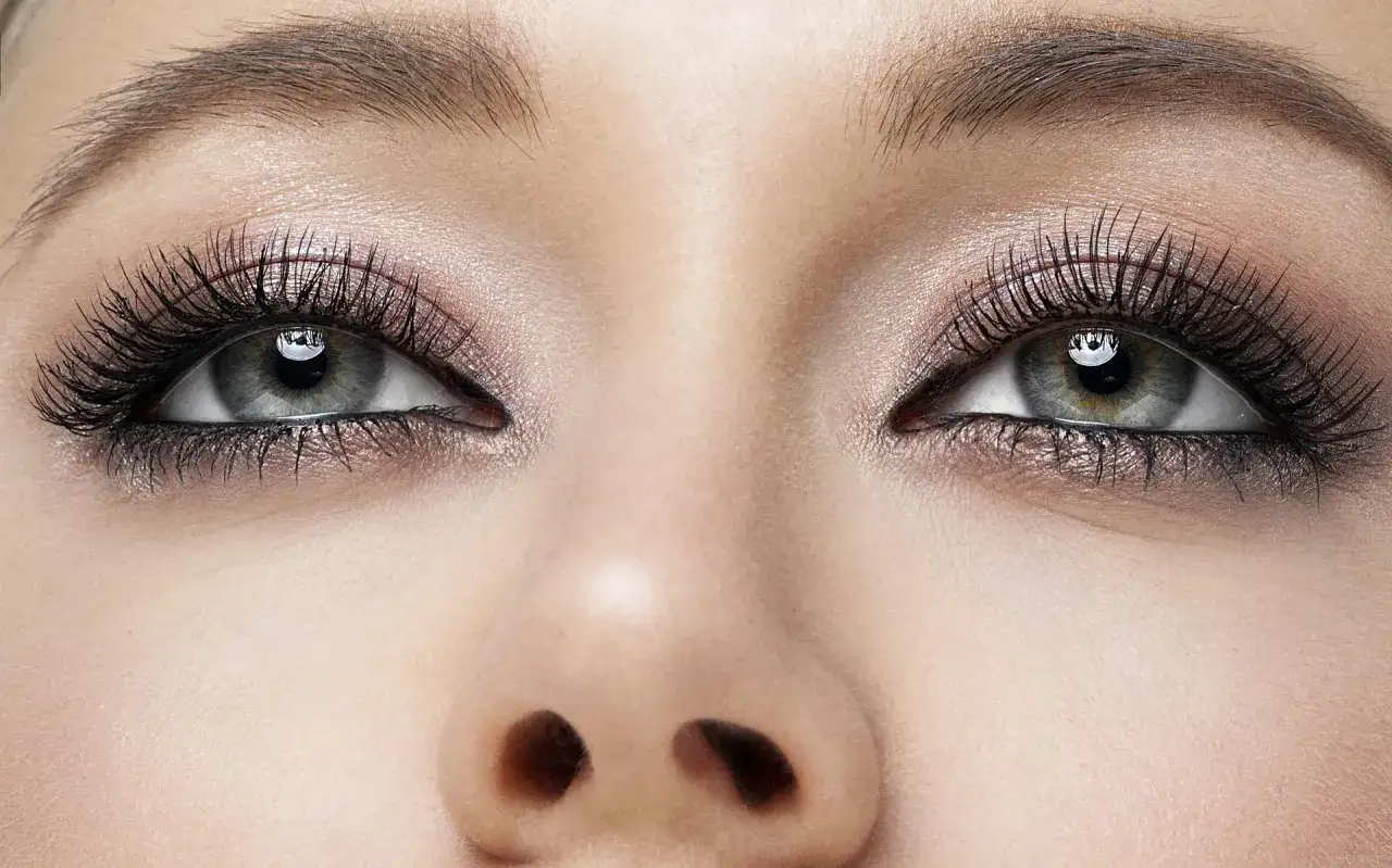 Oczy z perfekcyjnym makijażem smokey eye, długimi rzęsami i subtelnym połyskiem na powiekach.