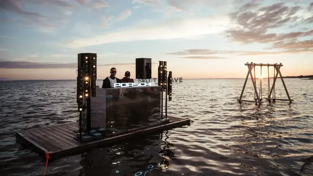DJ na wodnej platformie podczas Salt Wave Festival. W tle huśtawka na jeziorze o zachodzie słońca.