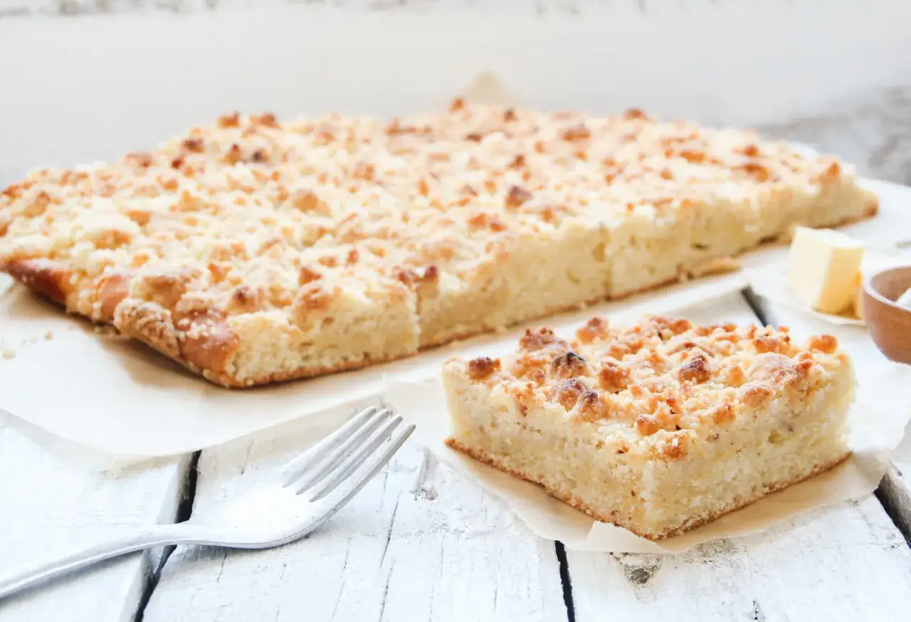 Ein Stück saftiger low carb streusel Kuchen mit Butter und einer Gabel auf einem Holztisch.