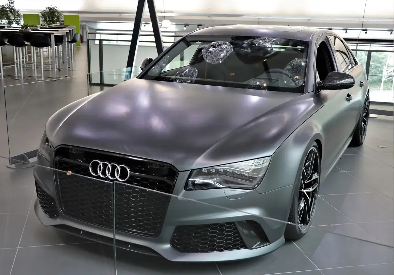 Matowy, szary Audi RS8 z czarnymi felgami i detalami, prezentowany w salonie.