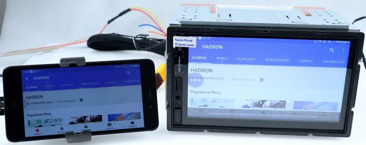Nowe radio samochodowe z ekranem i telefonem obok, pokazujące YouTube. To rozwiązanie ułatwia dołożenie bluetooth do radia samochodowego.