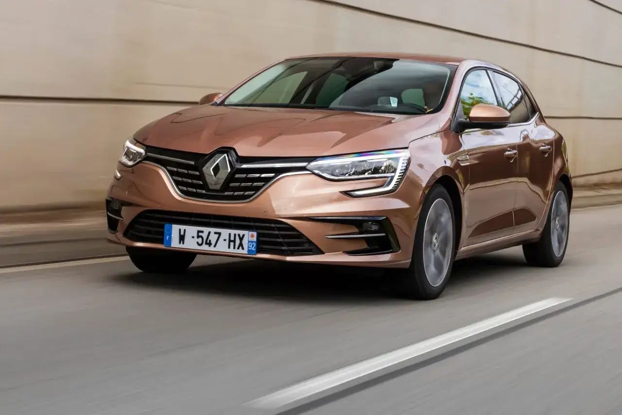Brązowy Renault Megane RS 4 pędzi po drodze, jego reflektory ostro świecą.