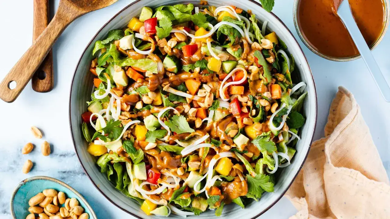 Bunter Sommerrollen Salat mit Reisnudeln, Mango, Avocado, Erdnüssen und cremiger Erdnusssauce.