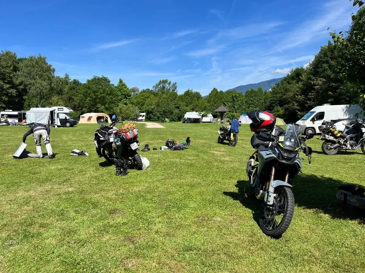 Motocykle zaparkowane na kempingu, w tle namioty i kampery.