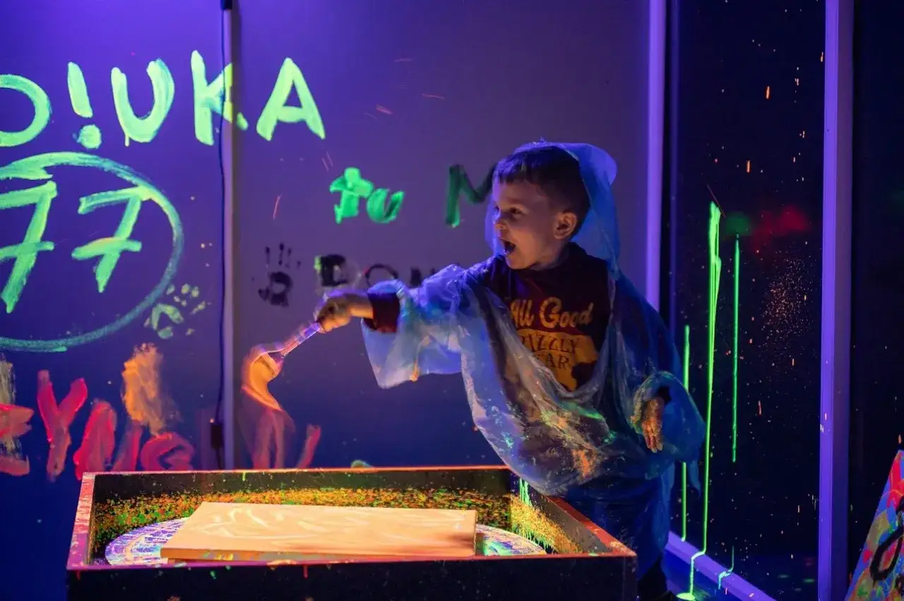 Chłopiec maluje farbami fluorescencyjnymi w ciemni. Niezapomniane urodziny dziecka w Szczecinie.