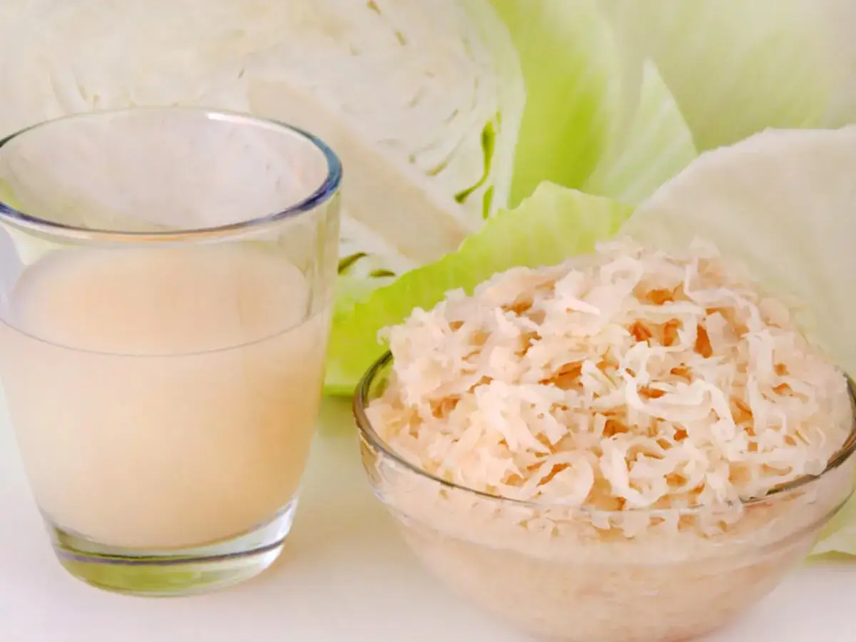 Glas mit Sauerkrautsaft, Schüssel mit Sauerkraut und Weißkohl. Ideal für eine Sauerkrautsaft Kur. Anleitung hier.