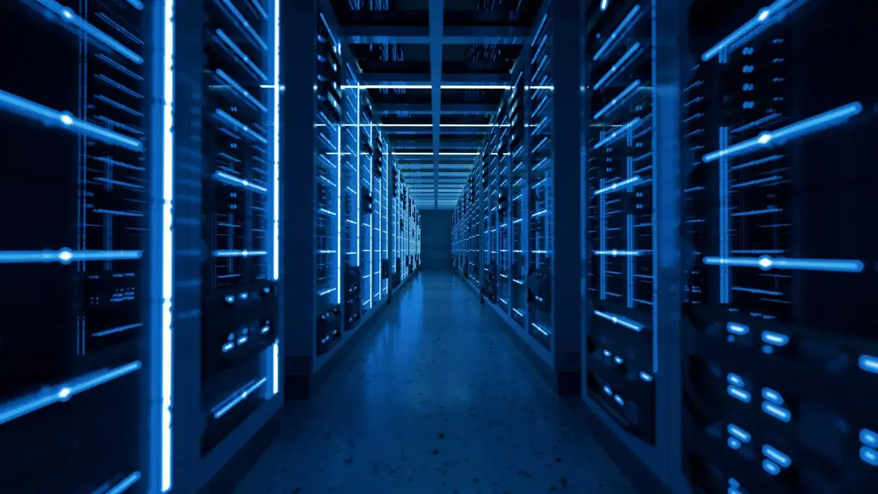 Wnętrze nowoczesnego data center z rzędami serwerów oświetlonych niebieskim światłem.