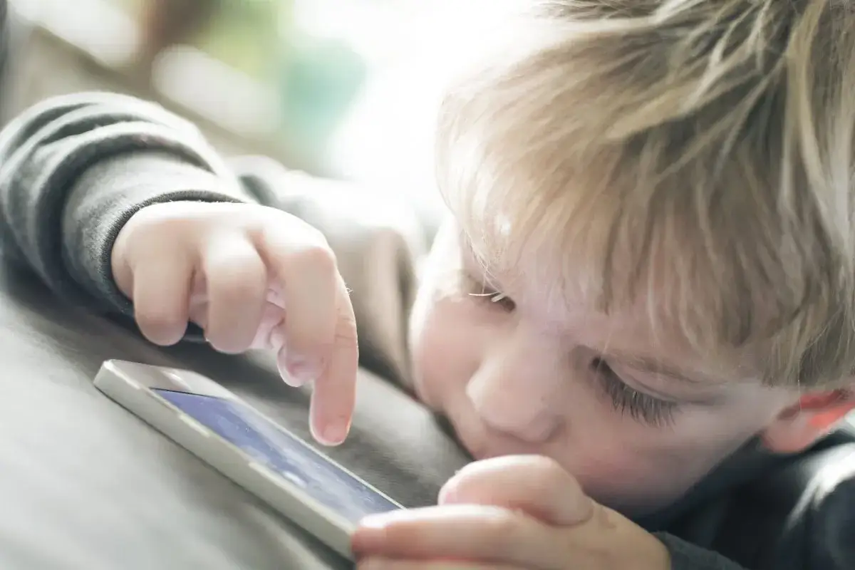 Un enfant blond joue sur un téléphone. Est-ce le wifi ou la 4G le plus dangereux pour lui ?