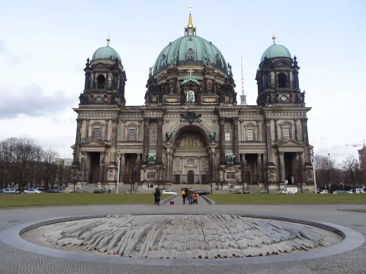 Majestatyczna katedra w Berlinie z zielonymi kopułami, na pierwszym planie kamienna rzeźba.