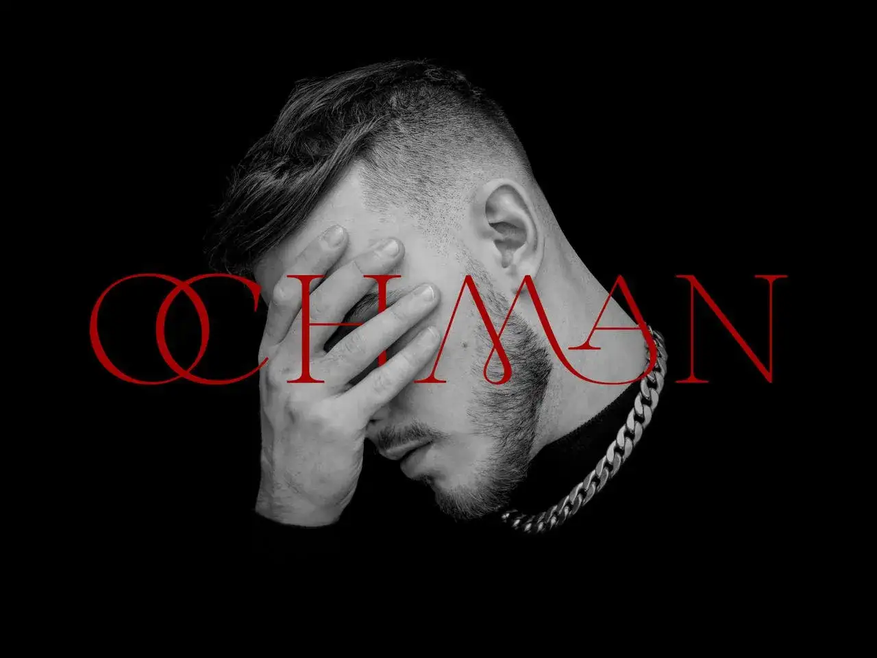 Krystian Ochman - nowa płyta. Artysta z dłonią na twarzy, w tle czerwony napis "OCHMAN".