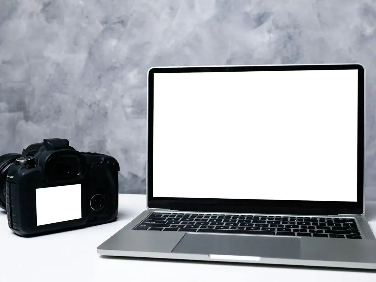 Aparat cyfrowy i laptop obok siebie. Idealne do nauki, jak przenieść zdjęcia z aparatu cyfrowego na telefon.