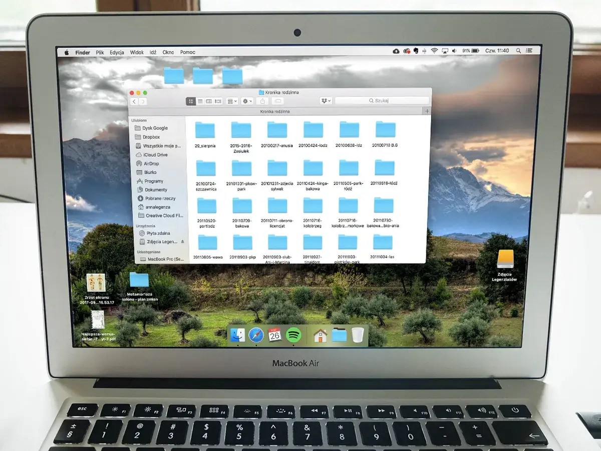 Na ekranie MacBook Air widać okno programu do segregowania zdjęć, z folderami o nazwach dat.