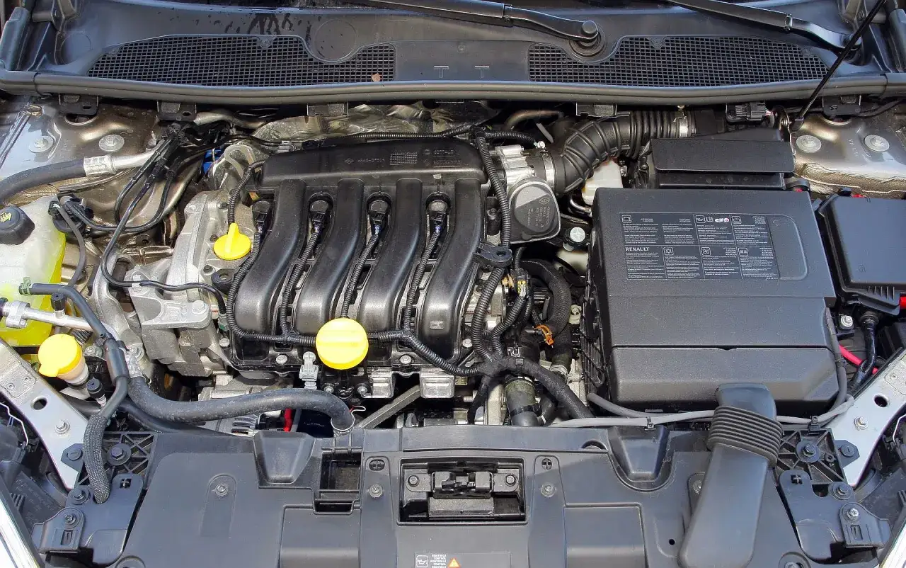 Silnik benzynowy Renault Megane 3, z widocznymi przewodami, cewkami zapłonowymi i żółtymi korkami.