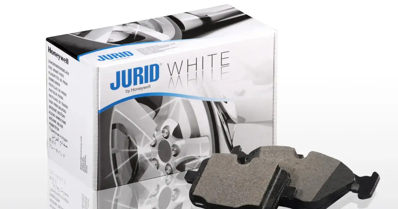 Dwa klocki hamulcowe Jurid White, wykonane z materiałów ceramicznych, leżą obok pudełka z tymi samymi klockami.