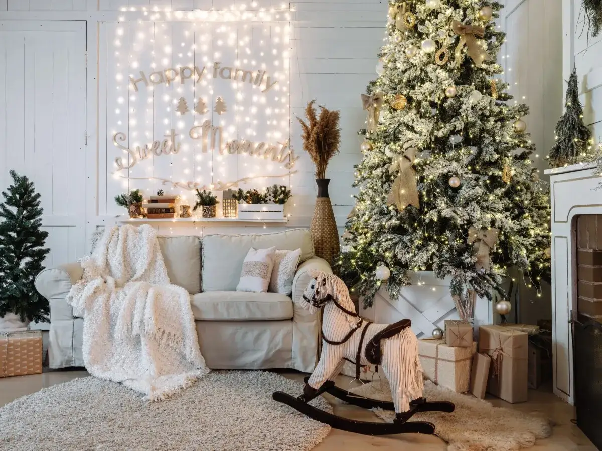 Ideas para decorar mi casa en navidad: árbol nevado, luces cálidas, sofá acogedor, caballito de madera y regalos.