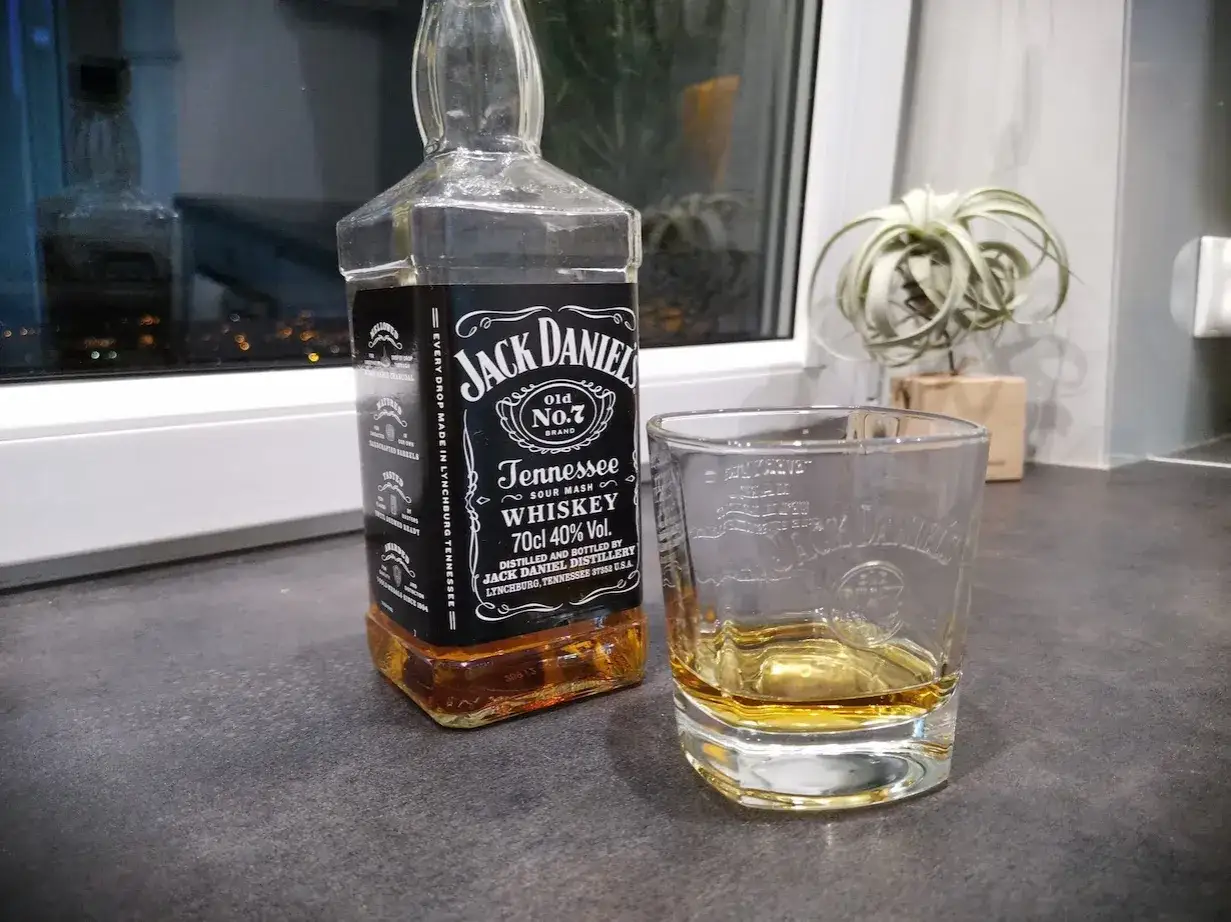 Butelka Jack Daniel's Tennessee Whiskey i szklanka z bursztynowym płynem. Idealny zestaw na wieczór.