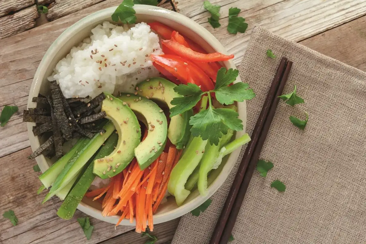 Bunte vegane Sushi Bowl mit Reis, Avocado, Karotten, Gurke, Paprika und Nori. Ein gesunder Genuss!