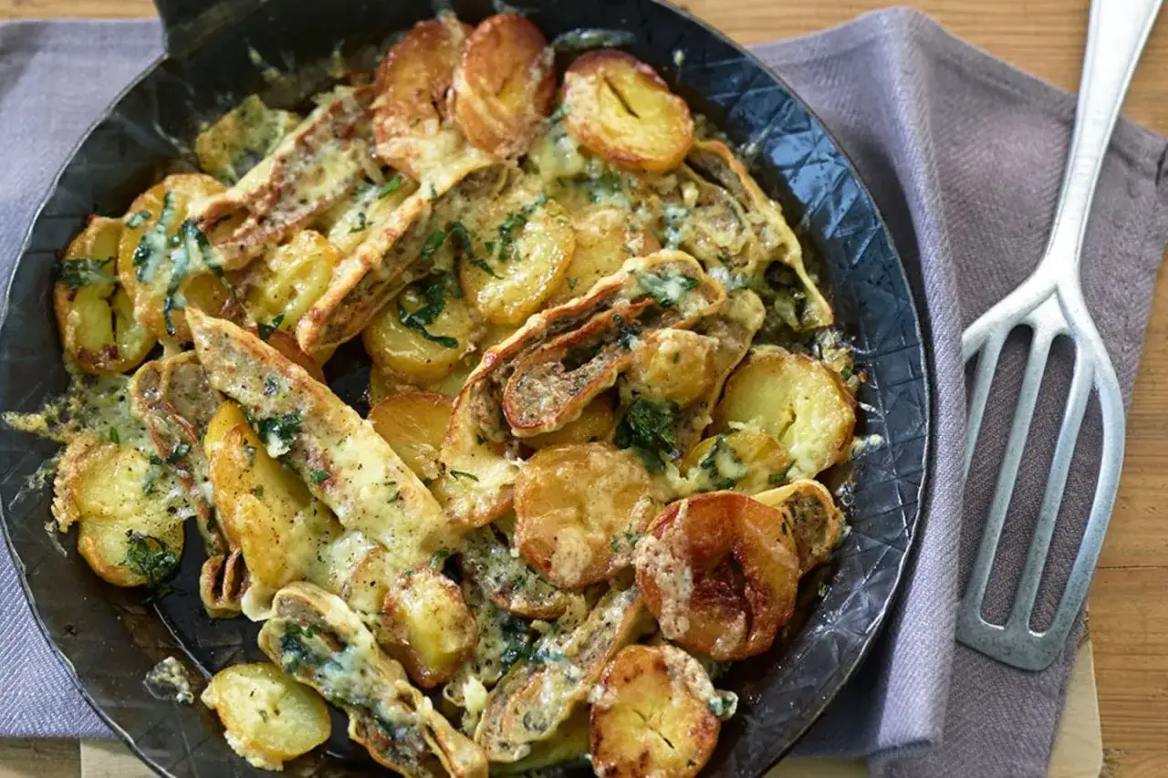 Herzhafte Maultaschen-Pfanne mit goldbraunen Kartoffelscheiben und geschmolzenem Käse, garniert mit frischen Kräutern.