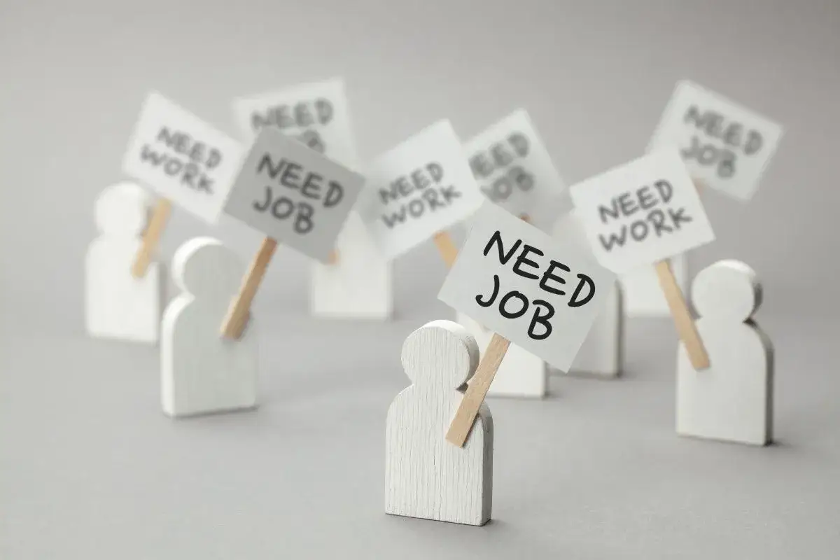 Figurki ludzi z transparentami "NEED JOB" i "NEED WORK". Dowiedz się, jak sprawdzić status bezrobotnego online.