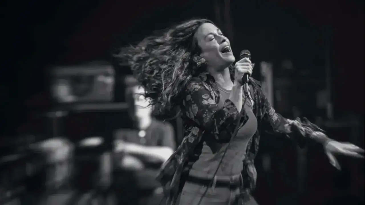 Energetyczny alanis morissette koncert, wokalistka śpiewa z pasją, włosy rozwiane w locie.