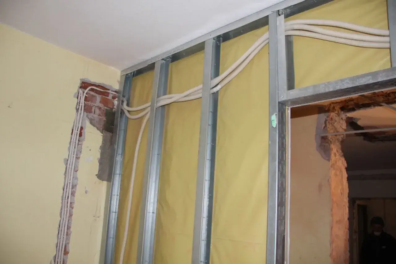 Nowa instalacja elektryczna bez kucia ścian. Widoczne profile metalowe, izolacja i nowe przewody w peszlach.