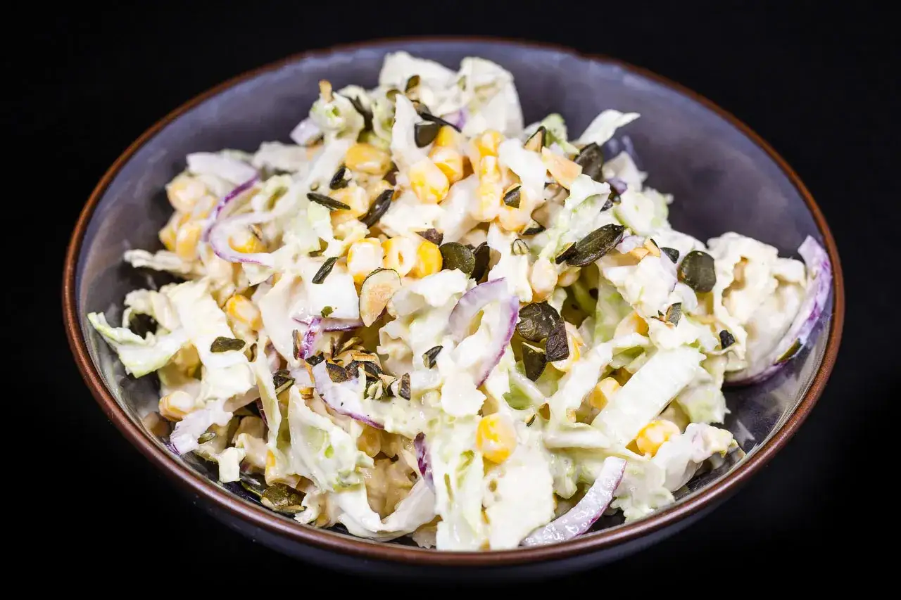 Frischer Chinakohl Salat mit Mais, roten Zwiebeln und Kürbiskernen in cremiger Soße.