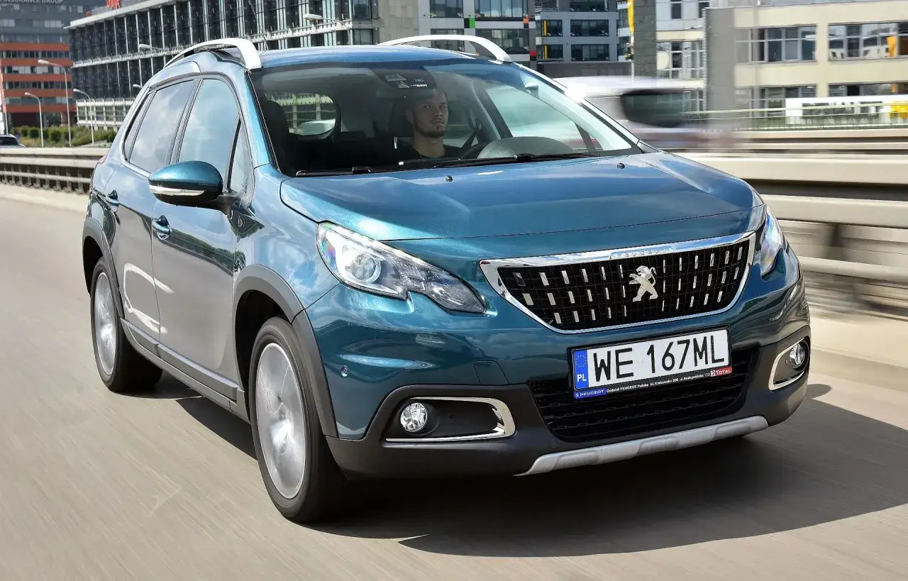 Turkusowy Peugeot 2008 na drodze. Kierowca w środku. Wiele pozytywnych peugeot 2008 opinie o tym modelu.