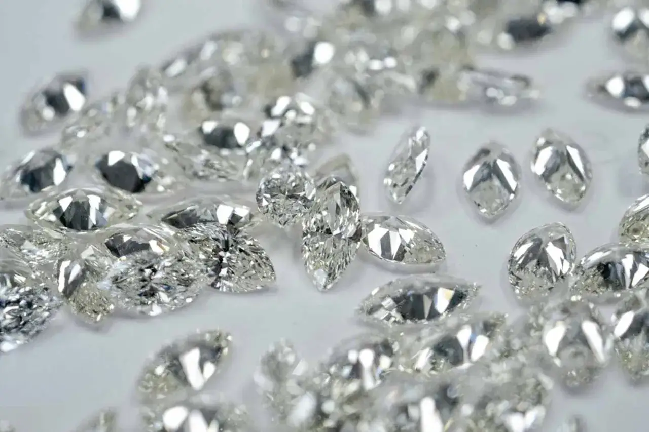 Glitzernde Diamanten in verschiedenen Schliffen, darunter Marquise und Tropfen, liegen verstreut. Ihr perfekter diamanten schliff fängt das Licht ein.