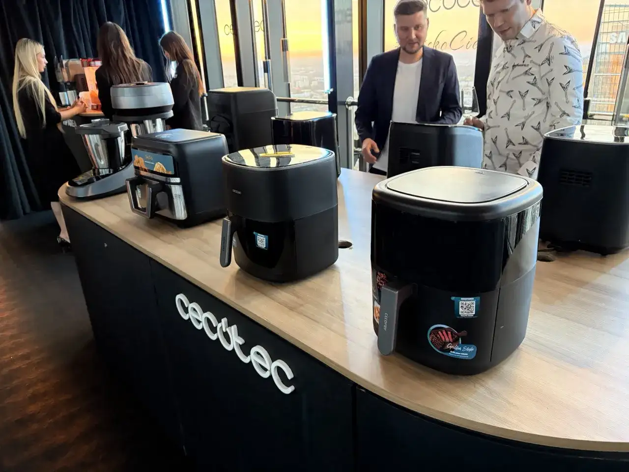 Prezentacja urządzeń kuchennych marki Cecotec. Na ladzie stoją frytkownice beztłuszczowe i robot kuchenny.