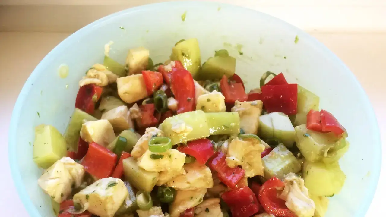 Frischer Salat mit gewürfeltem Gemüse und Käse, verfeinert mit Pesto.