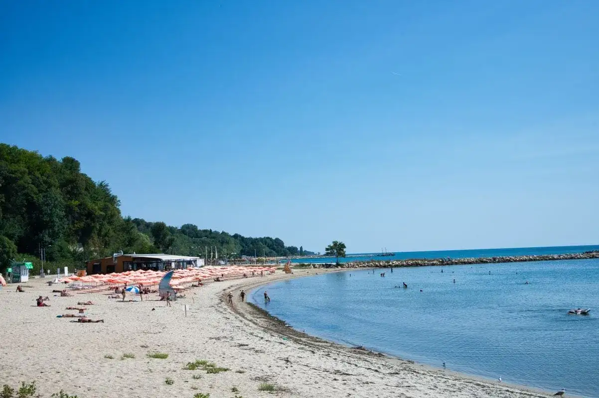 Słoneczny dzień na plaży w Złote Piaski, Bułgaria. Piasek, morze i mnóstwo pomarańczowych parasoli.